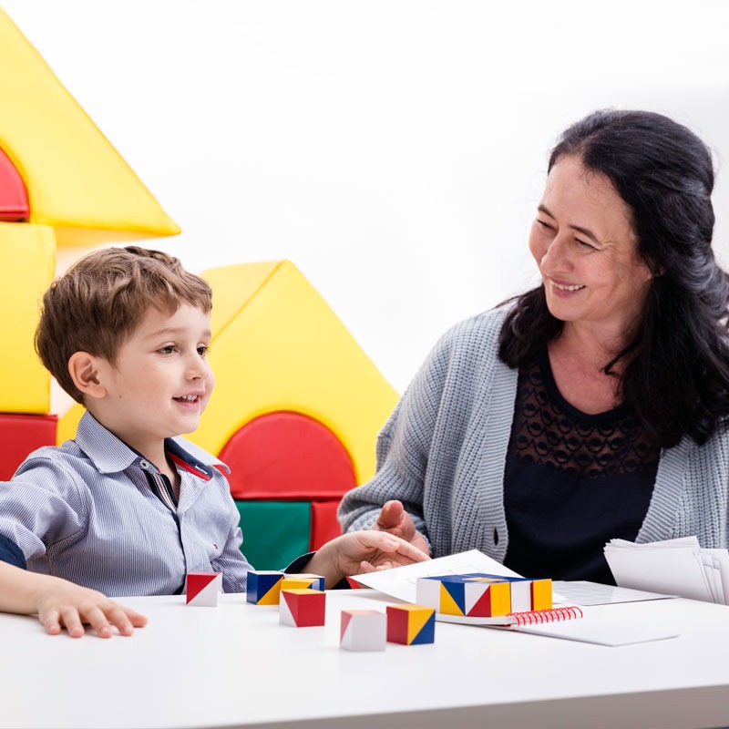 Petra Schönberger und Bub in Ergotherapie mit bunten Würfel